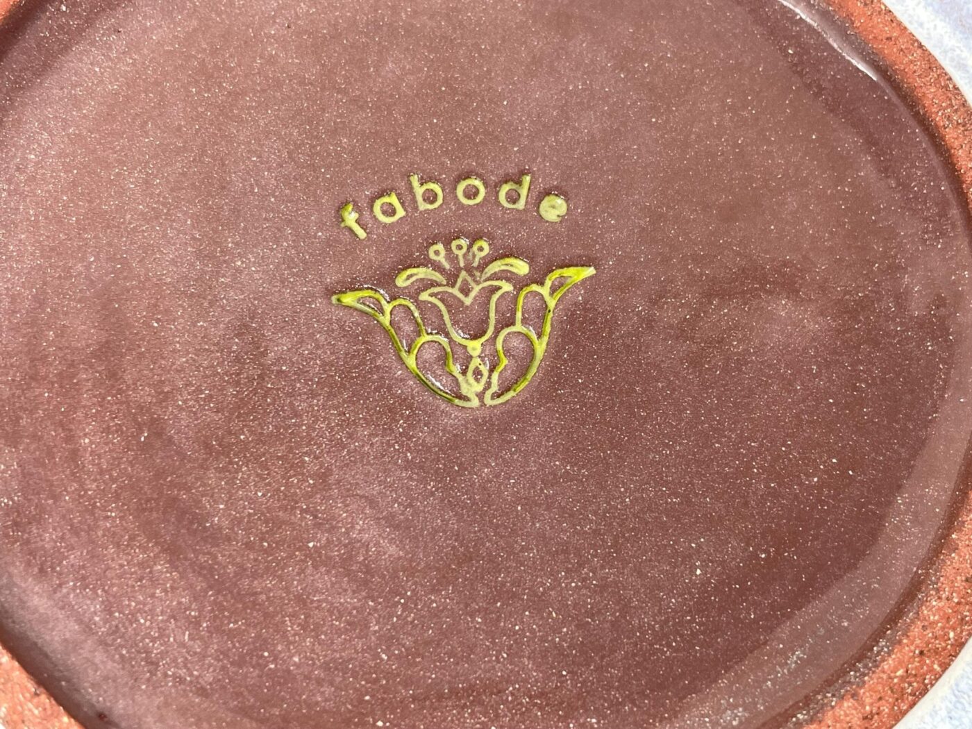 Ceramic plate with hand-scratched sunflower — maker's stamp detail — Fabode Ceramics