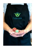 Marta in a Fabode apron holding two ceramic strawberries, hand-built at the Edinburgh studio