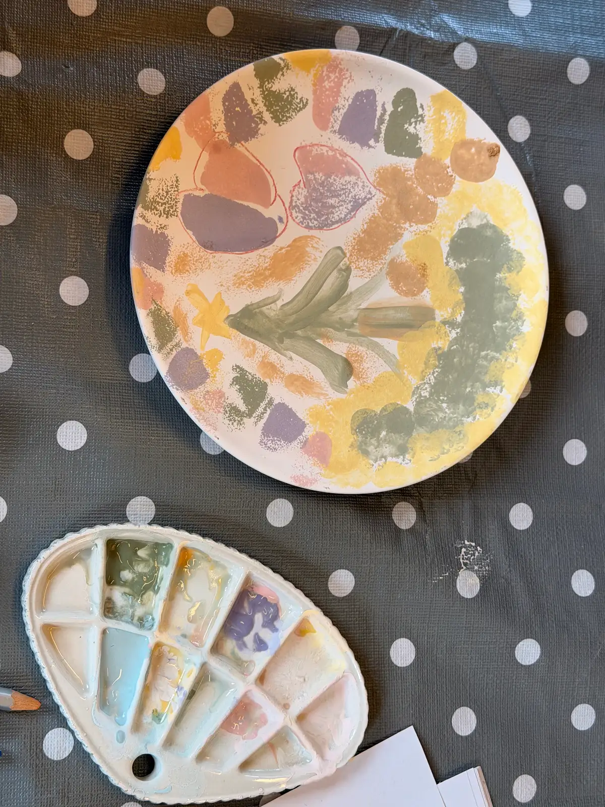 Painted ceramic plate and palette during a Fabode pottery painting session