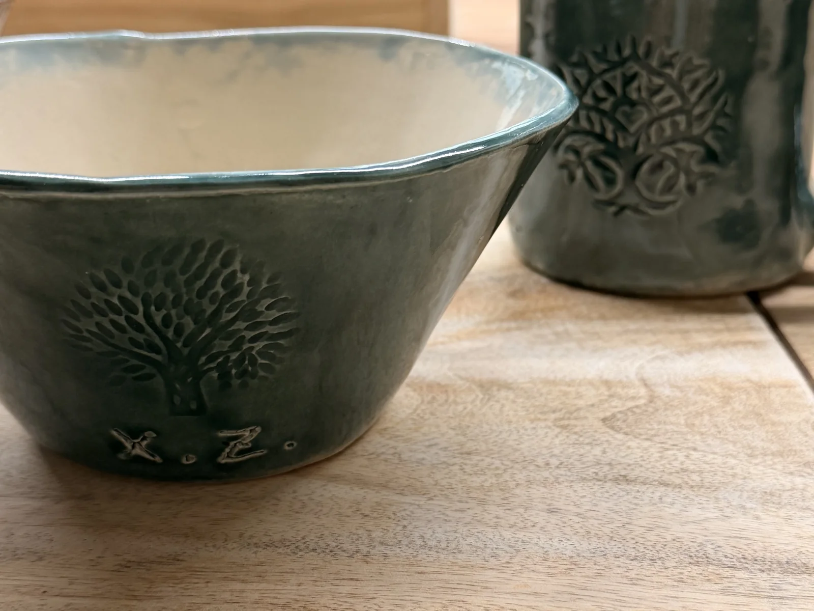 Deep green mug and bowl with tree motifs after glazing and firing