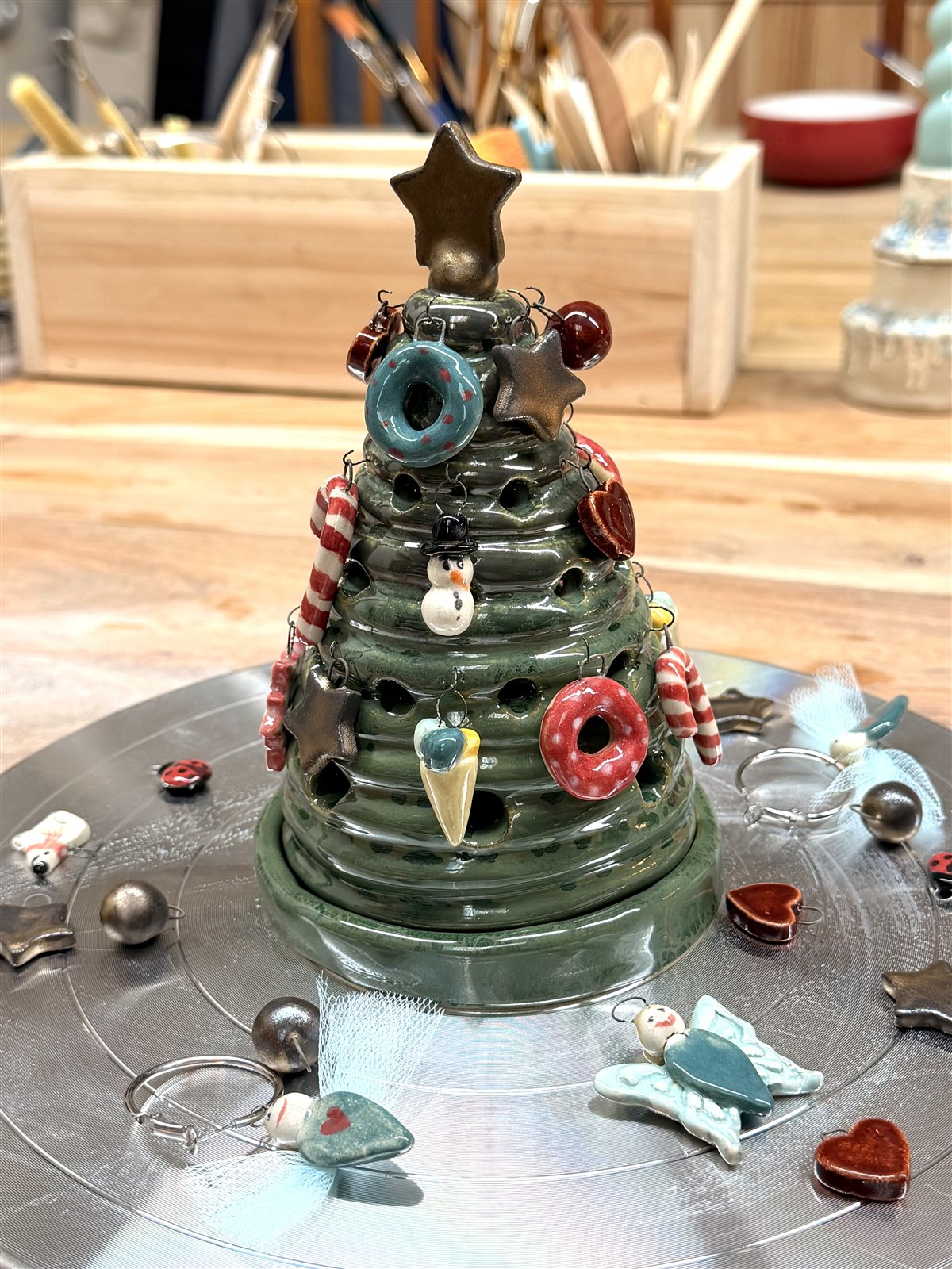 Green glazed ceramic Christmas tree with a gold star and colourful handmade hanging ornaments